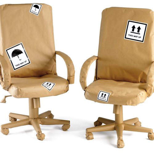 Office chairs wrapped up in brown paper ready for a move isolated on a white background